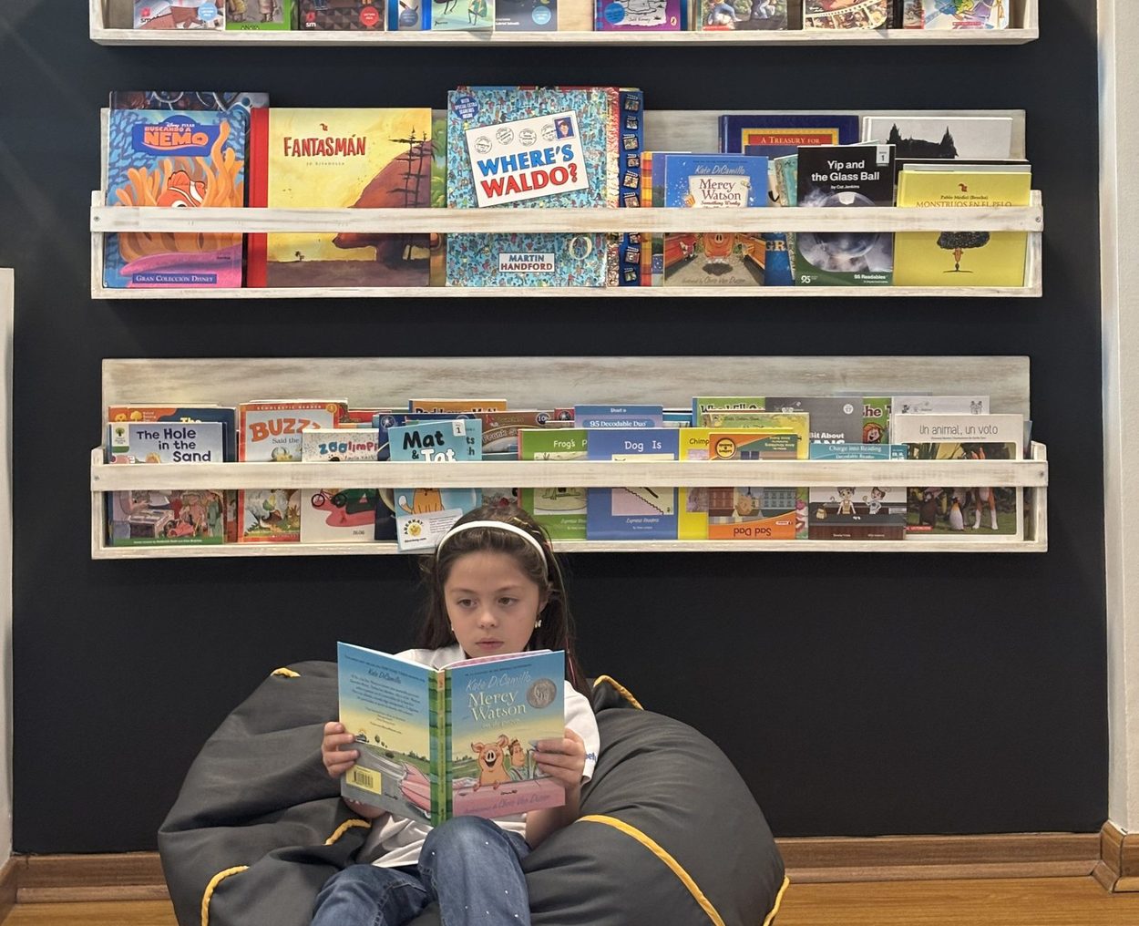 Niña leyendo un libro en el rincón de lectura
